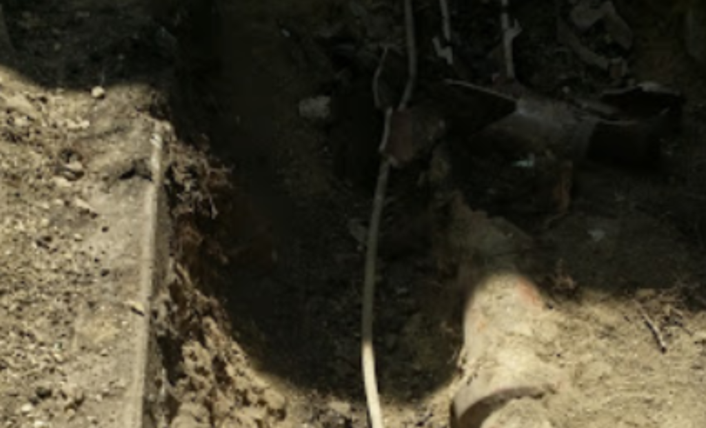 Trench exposing a buried sewer pipe