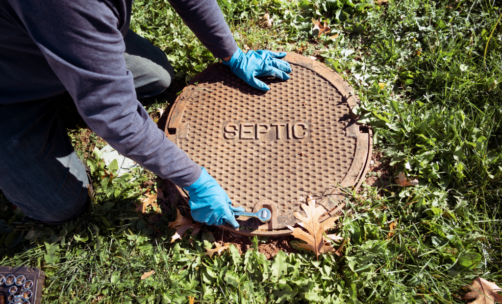 Technician opening a sewer access cover in a lawn