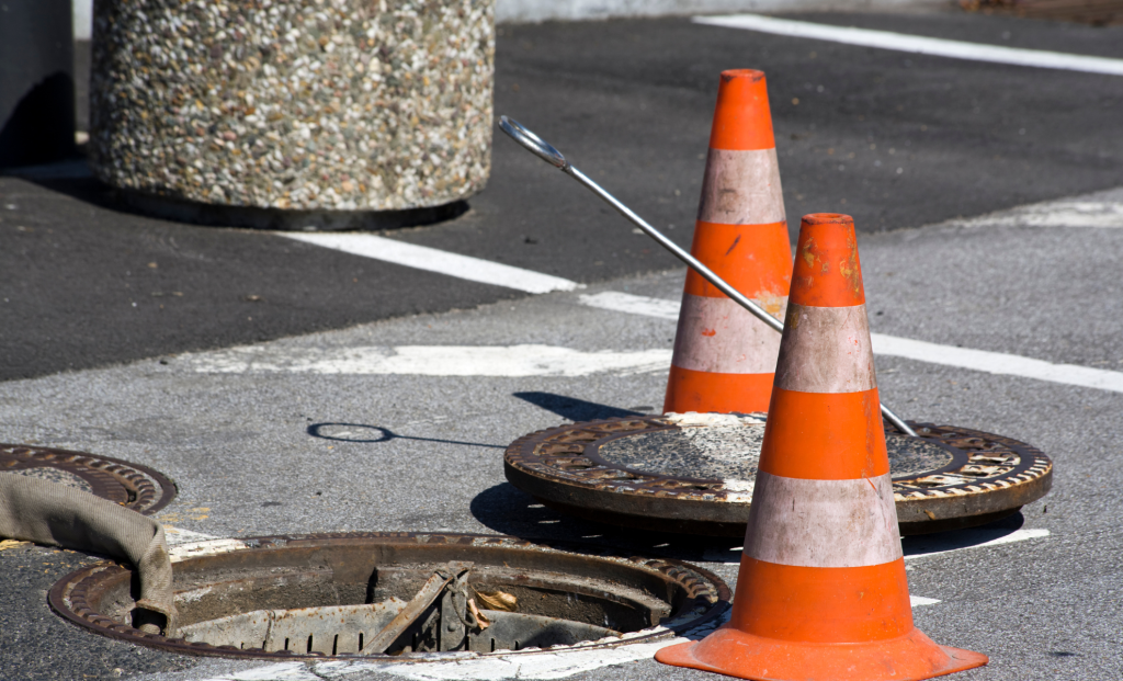 Traffic cones around an open street sewer access point