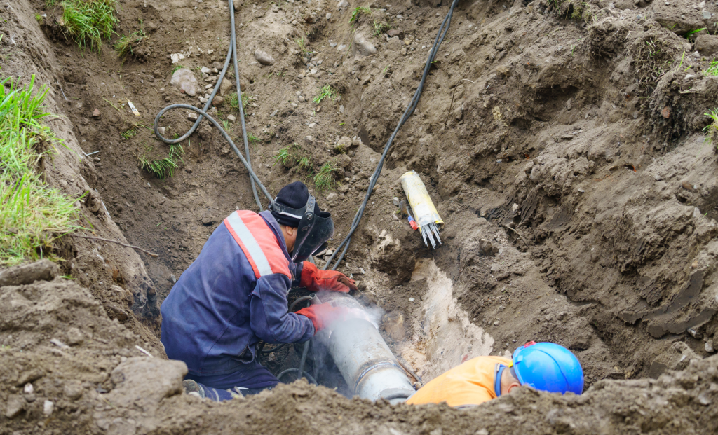 Workers repairing a sewer pipe in a deep excavation