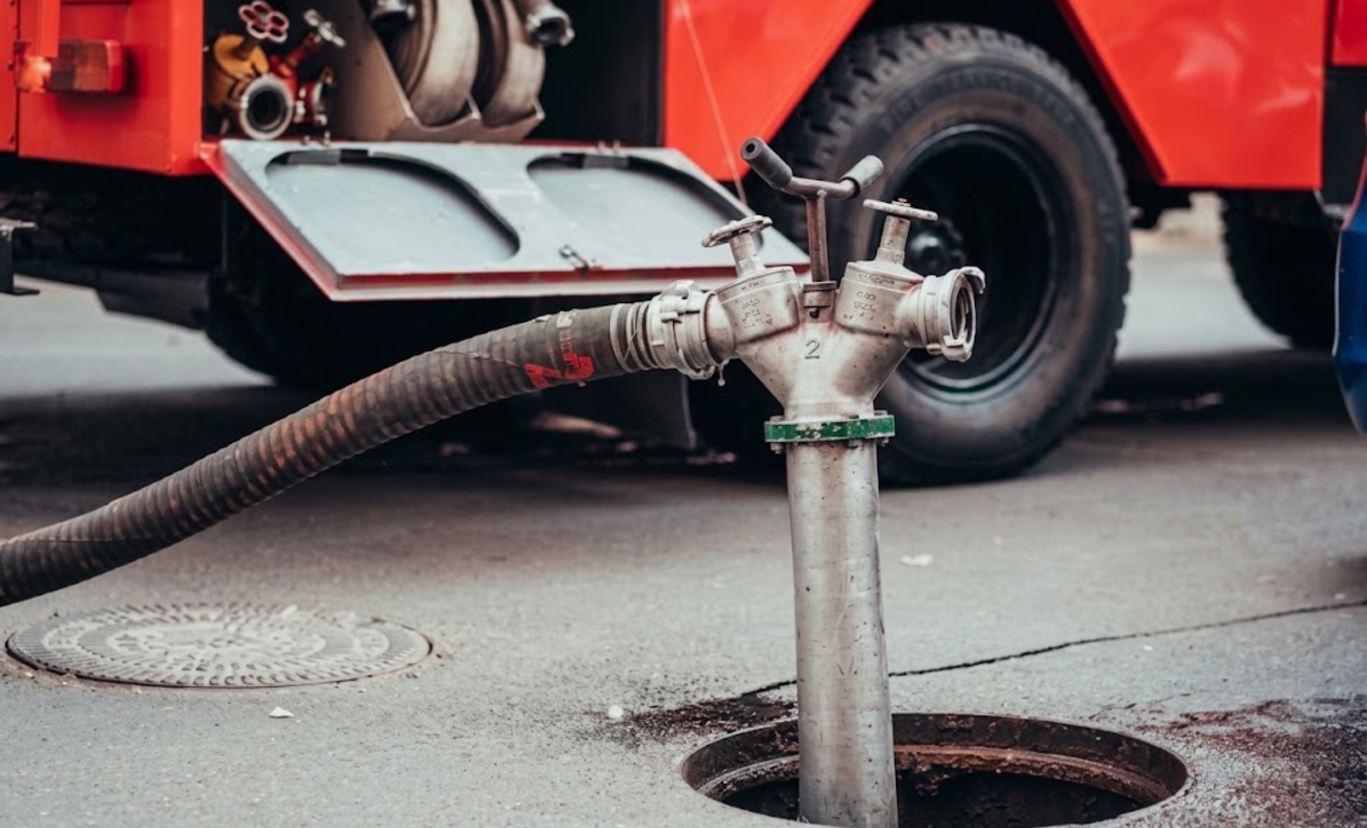 Sewer service truck hose connected to a pipe over an open sewer access point